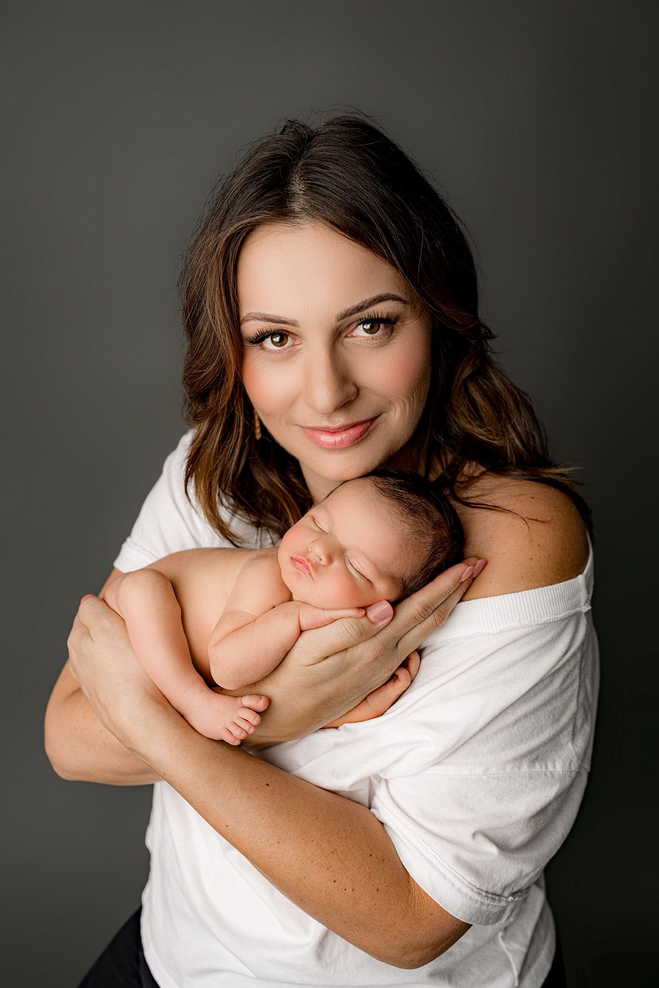 Charlotte mom holding her newborn son cradled in her arms posed in her hands