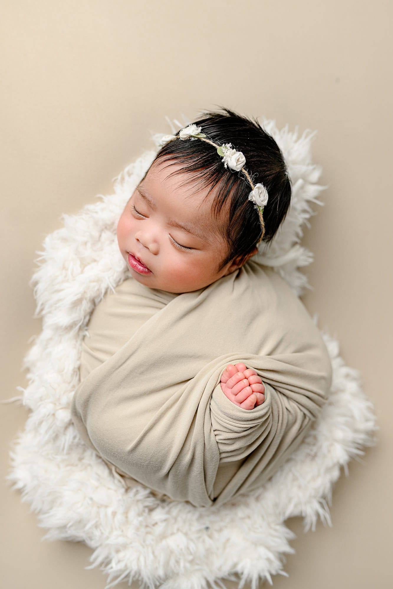 Neutral baby photo with baby wrapped with floral headpiece