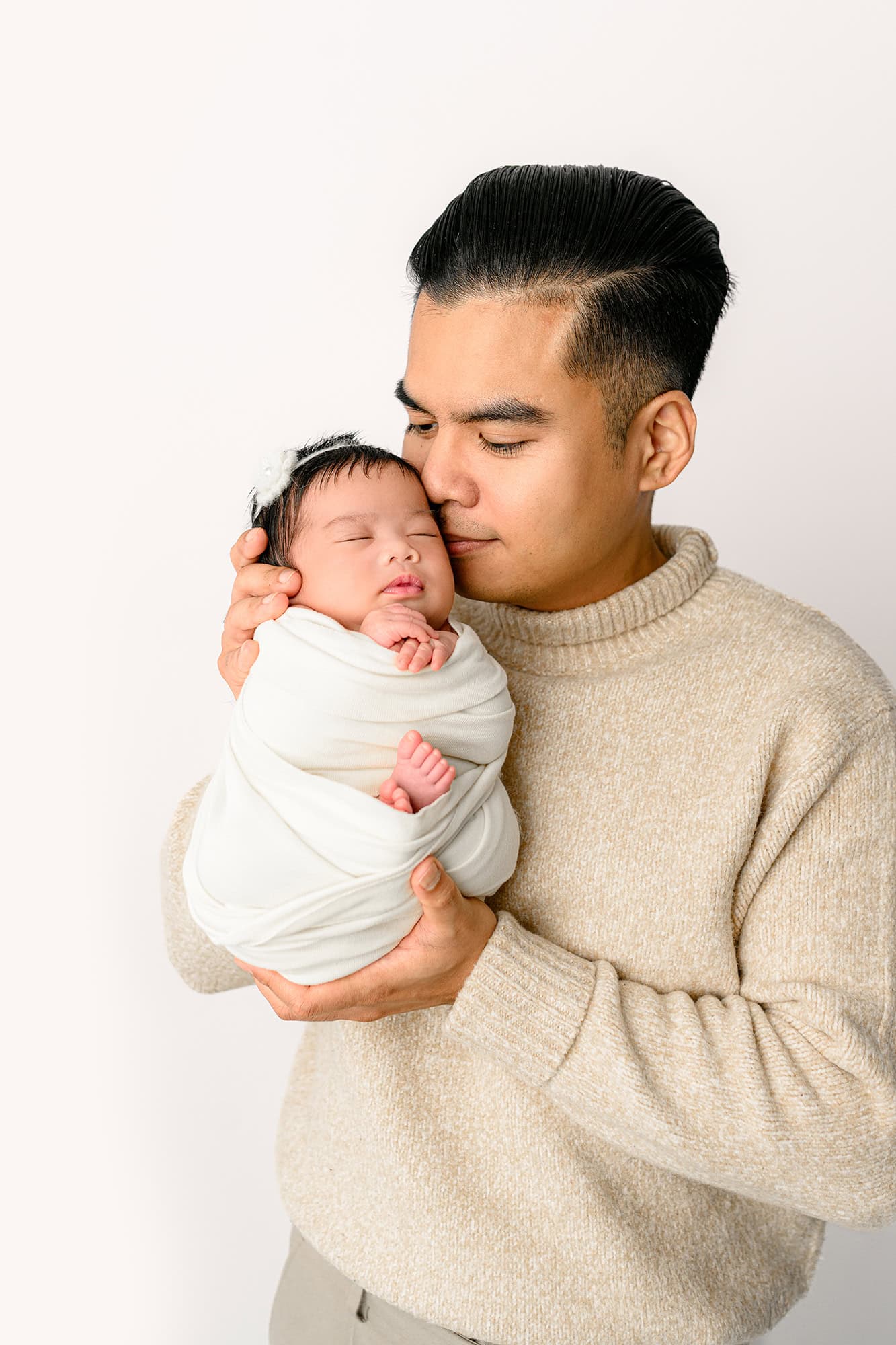 Dad holding his daughter in a studio newborn session after having a neutral themed baby shower