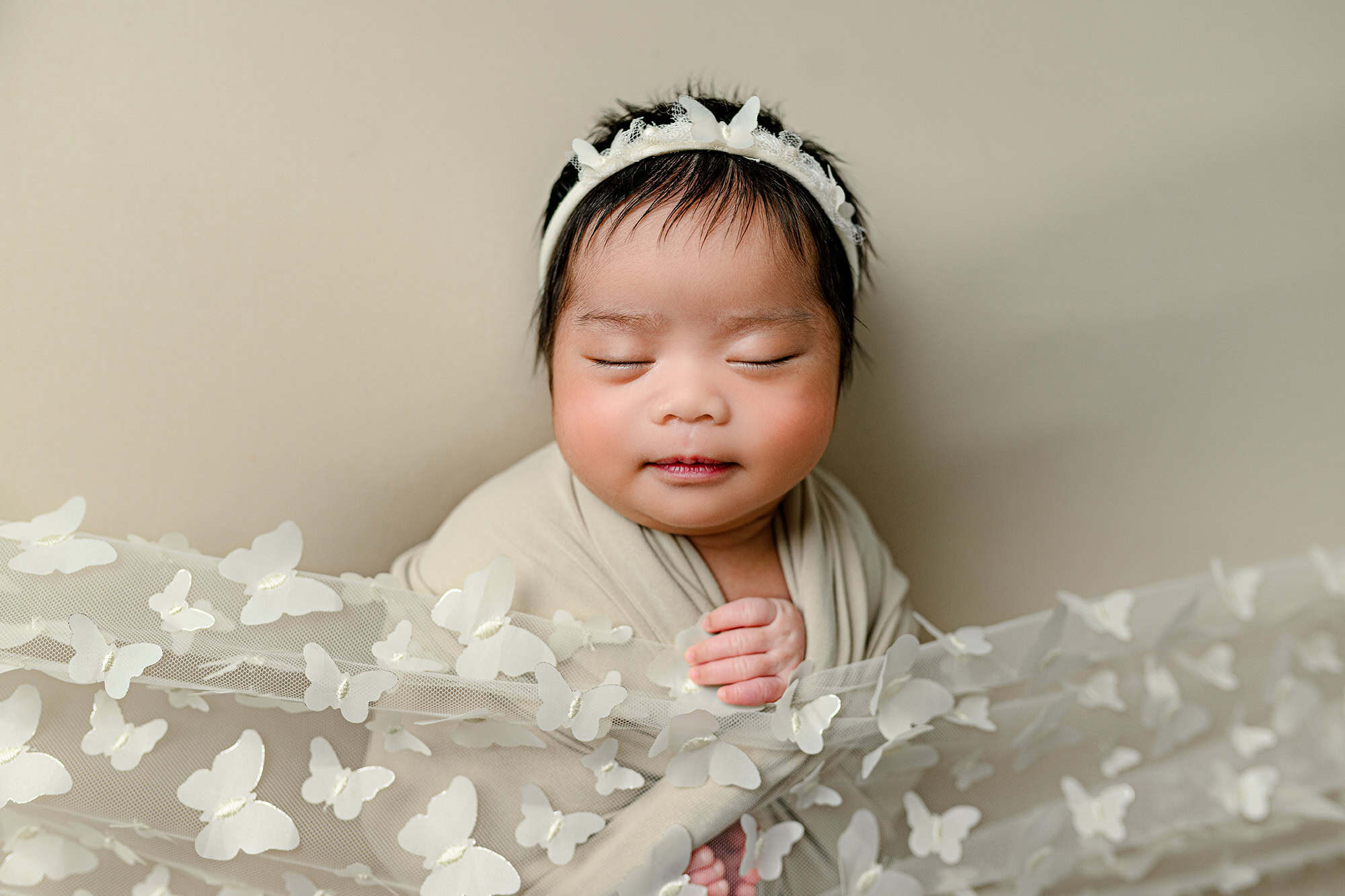 Baby girl wrapped in a neutral wrap with butterfly accents to compliment her woodland baby shower theme