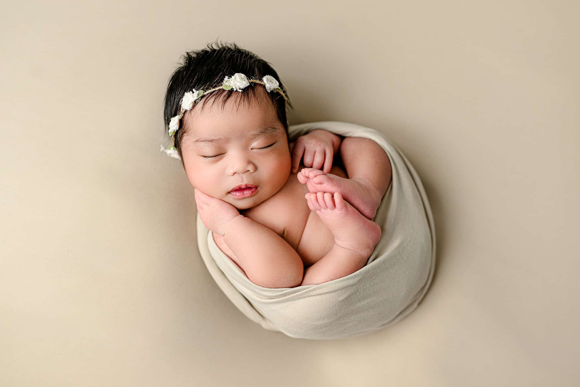 Charlotte Baby posed on her back in a neutral set up with a floral headpiece