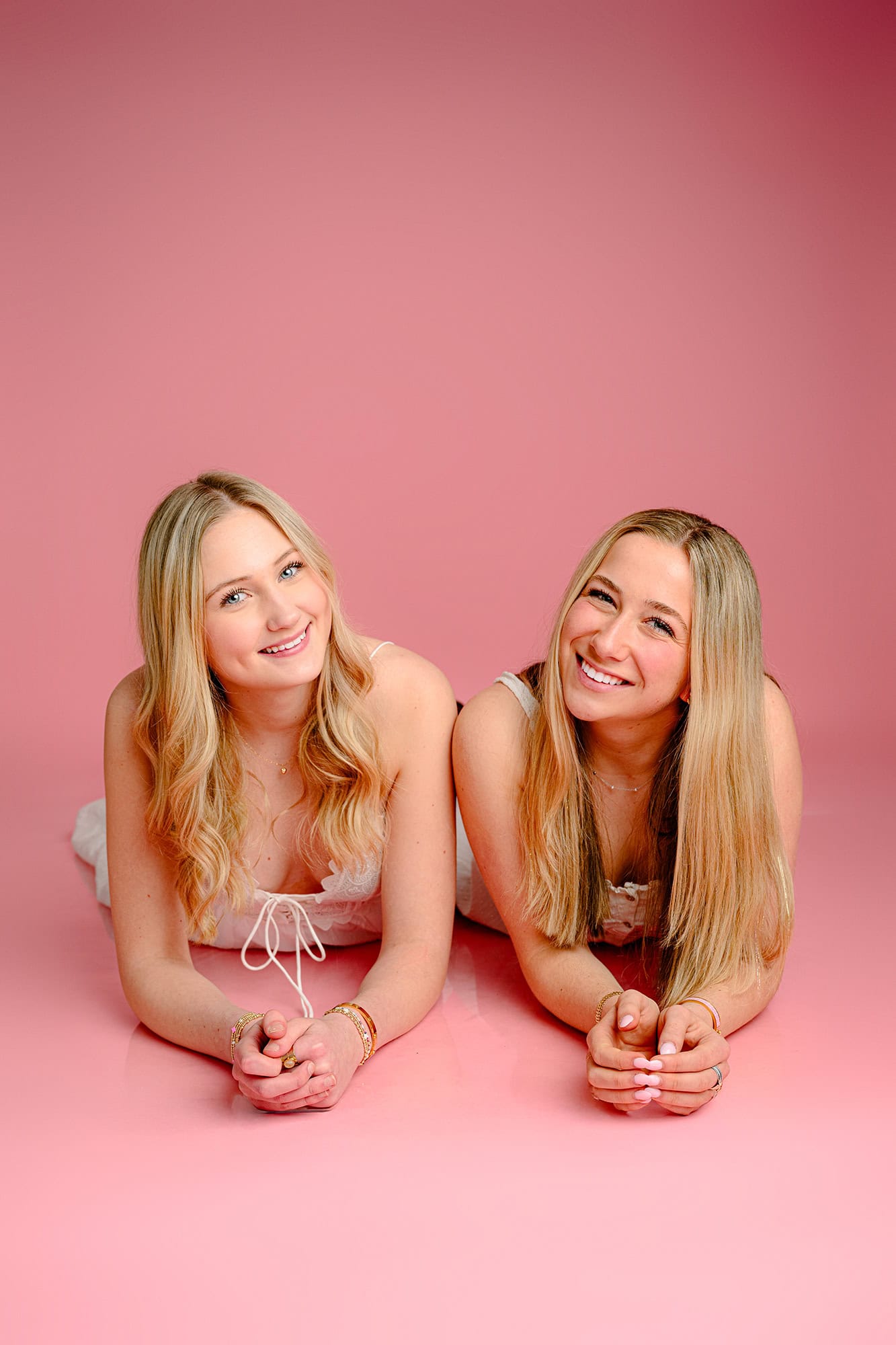 Charlotte catholic bestie mini session with two blonde graduates laying side by side