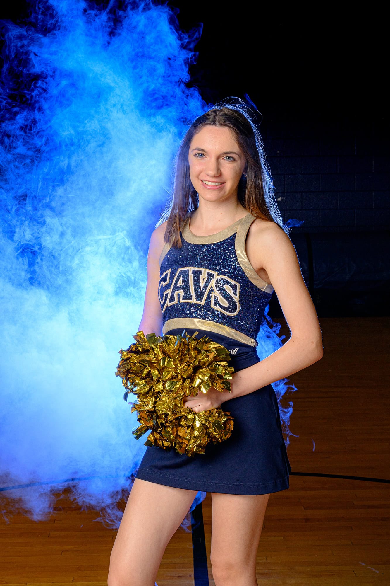 blue light behind dancer highlighting her hair with poms in her hand