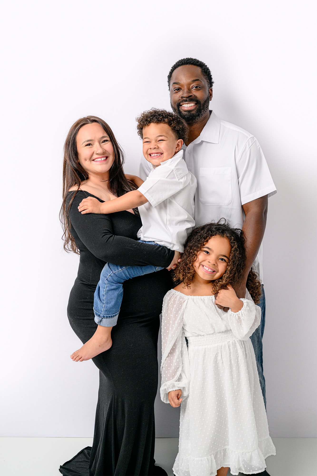 family of four wearing white and black during maternity studio photos