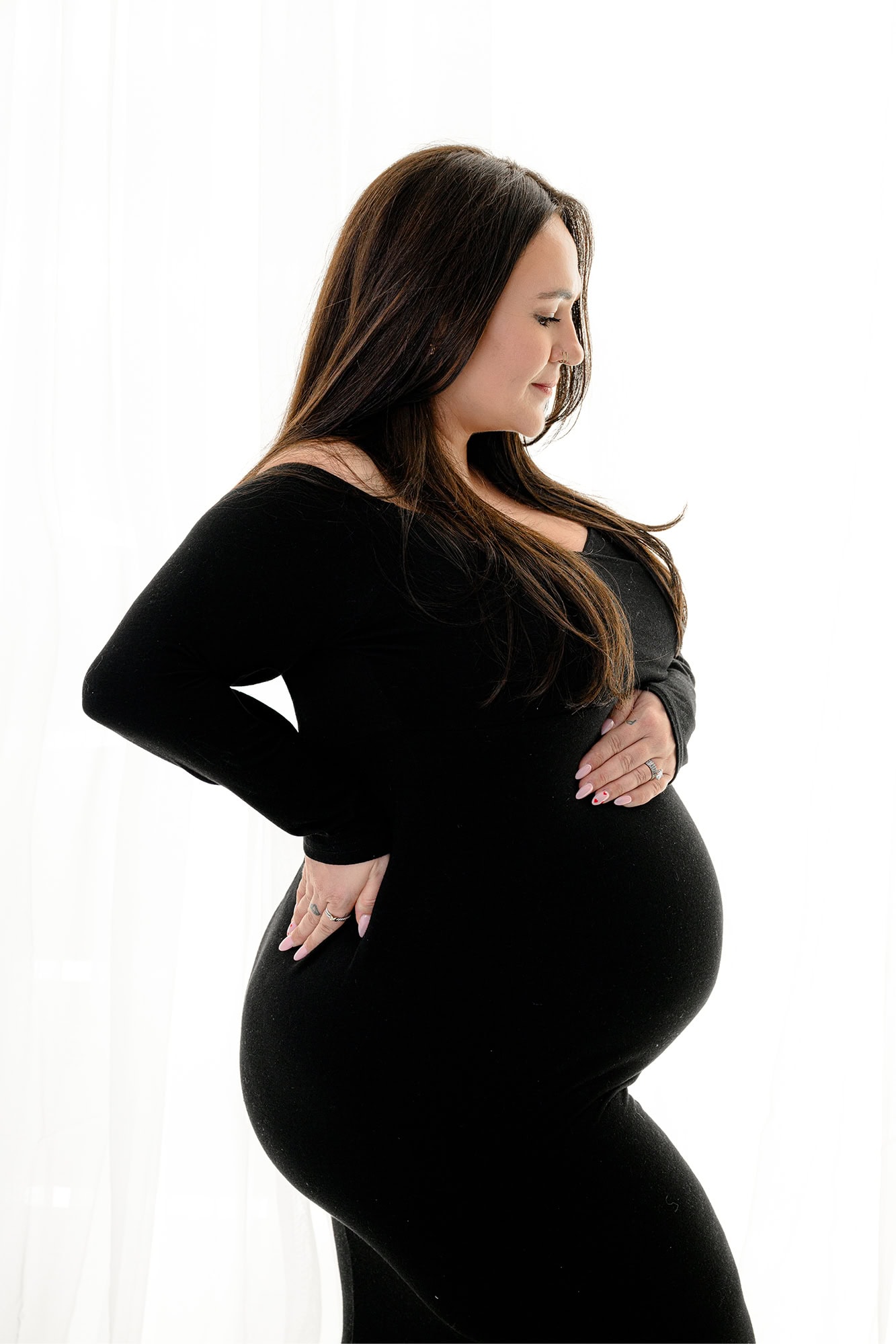 pregnant charlotte mom posed with arm on hip and hand on belly wearing a black maternity dress before her hospital birth