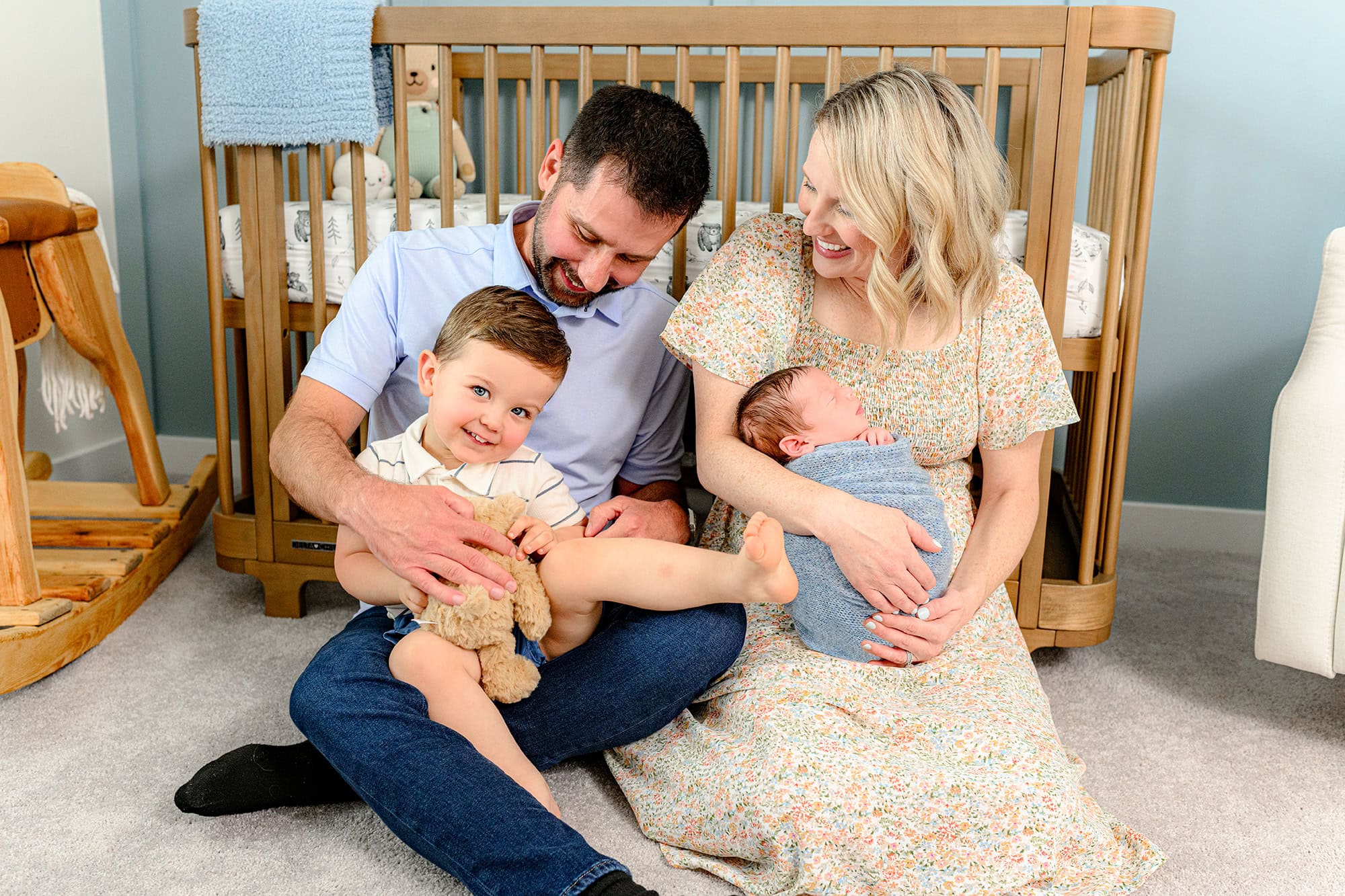 mom holds newborn and dad holds toddler during lifestyle newborn session 